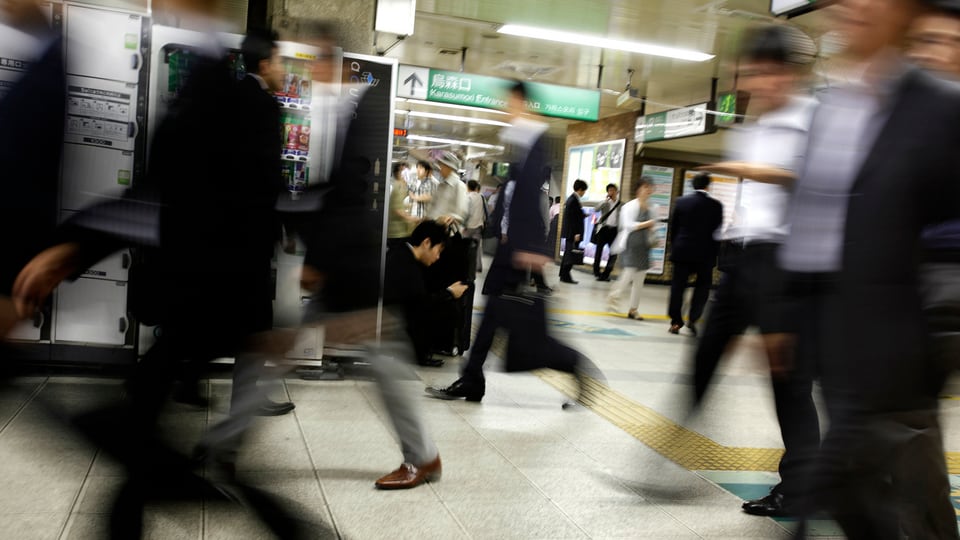Japaner eilen durch einen Bahnhof.