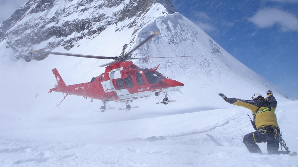 Der Gebirgshelikopter landet auf einem schneebedeckten Berg.