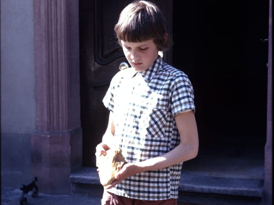 Altes Foto mit einem 12-Jährigen, der einen Stein in den Händen hält.
