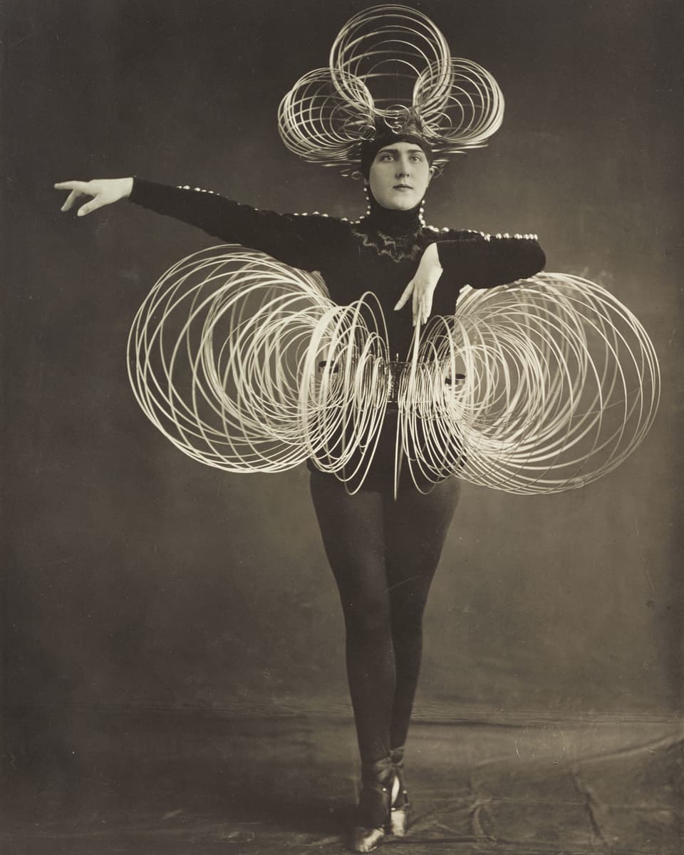 Alte Schwarz-weiss-Aufnahme einer Tänzerin in einem Kostüm mit Kreisen aus Draht, die einen Rock bilden