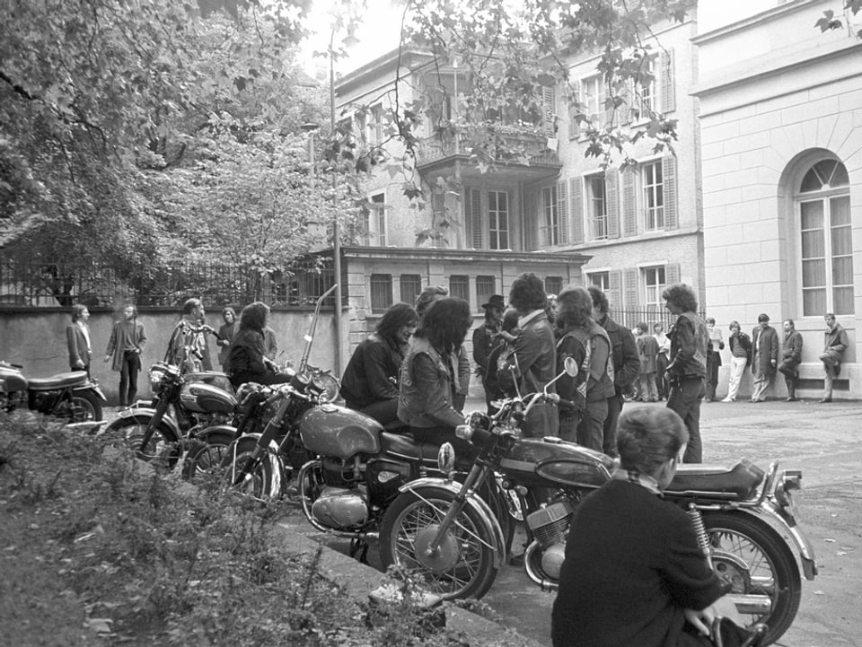 Schwarzweiss-Aufnahme von Bikes und Personen vor dem Gericht.