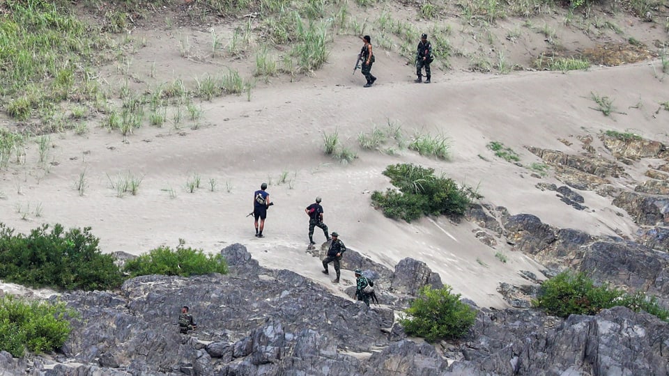 Bewaffnete Soldaten patrouillieren in einer felsigen Umgebung.