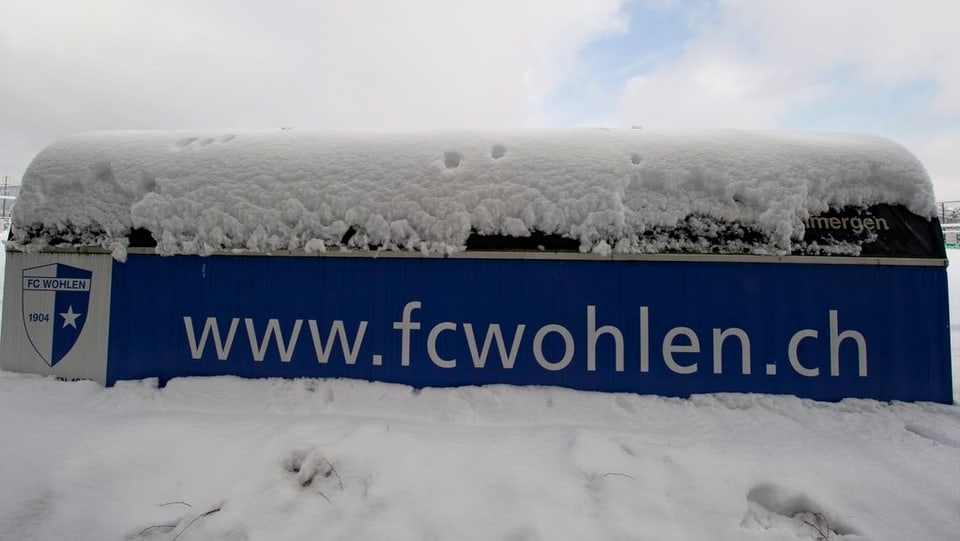 Schneebedecktes Plakat des FC Wohlen im Stadion Niedermatten.