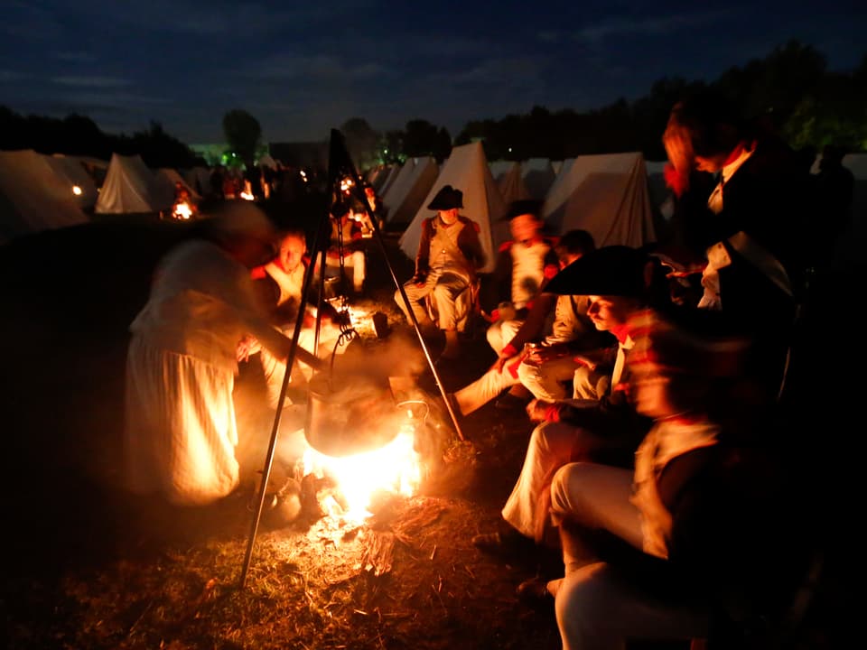Französische Truppen sitzen abends um ein Feuer und essen zu Abend. 
