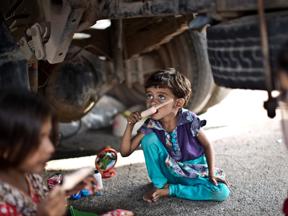 Kinder essen ein Eis unter einem Lastwagen 