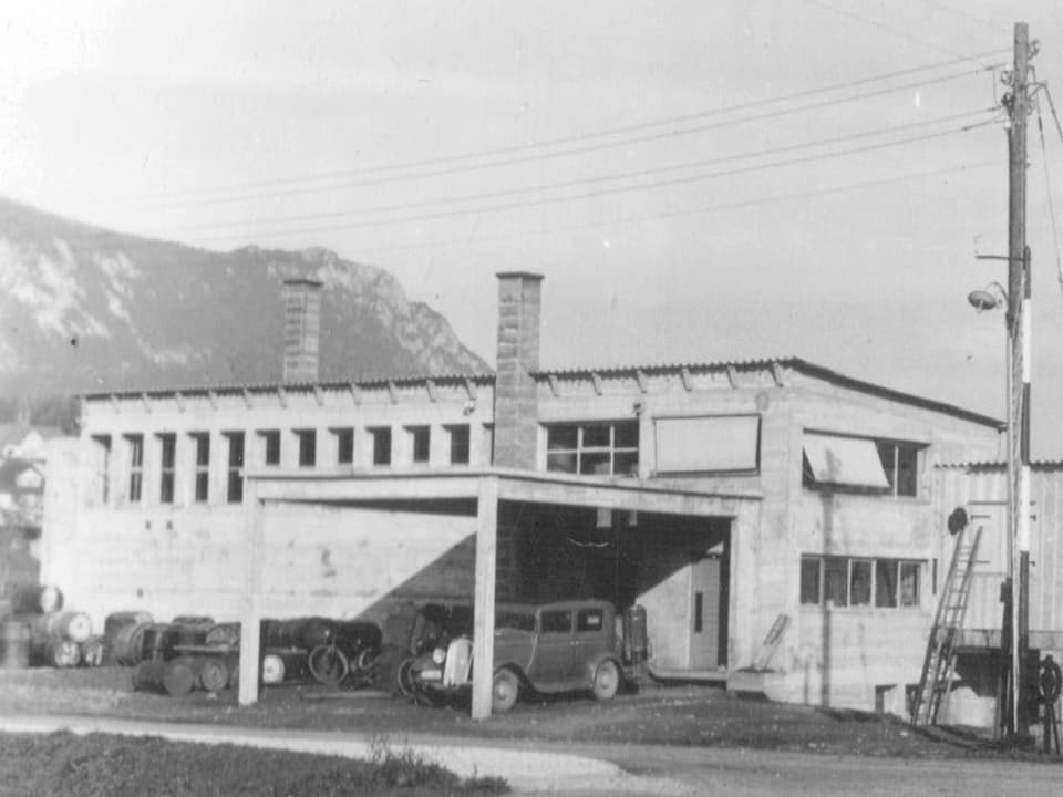 Schwarz-weiss-Foto eines Gebäudes, davor ein altes Auto.