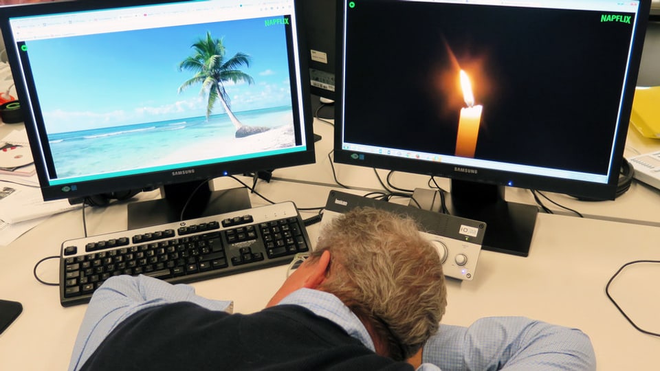 Ein Mann ist vor zwei Computerbildschirmen eingeschlafen.