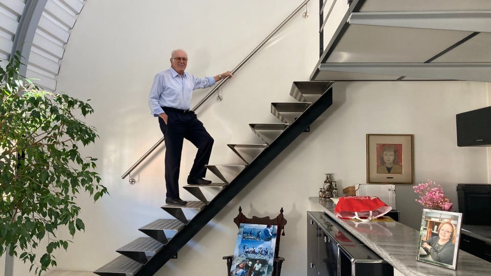 Älterer Mann steigt eine moderne Treppe in einem hell erleuchteten Haus hinauf.