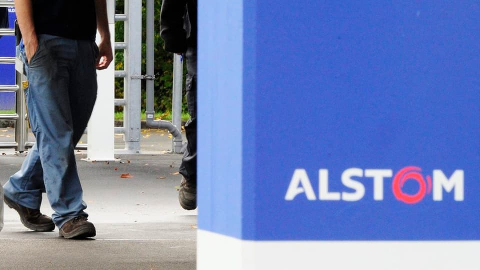 Ein Mann geht hinter einem Schriftzug Alstom hindurch