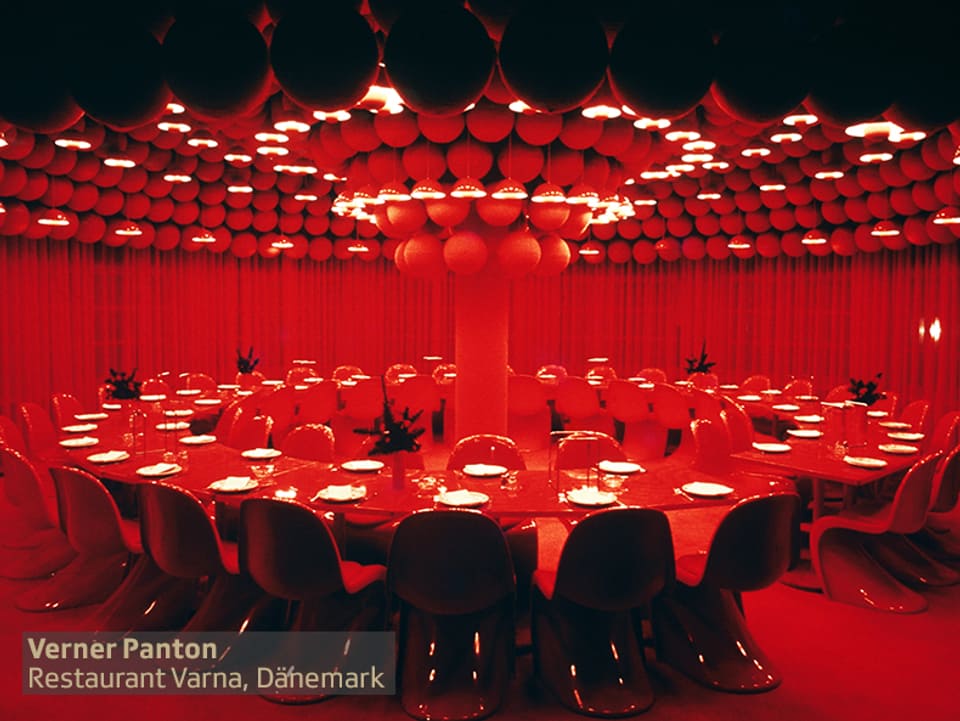 grosser runder roter Tisch mit weissen Tellern in komplett rotem Raum