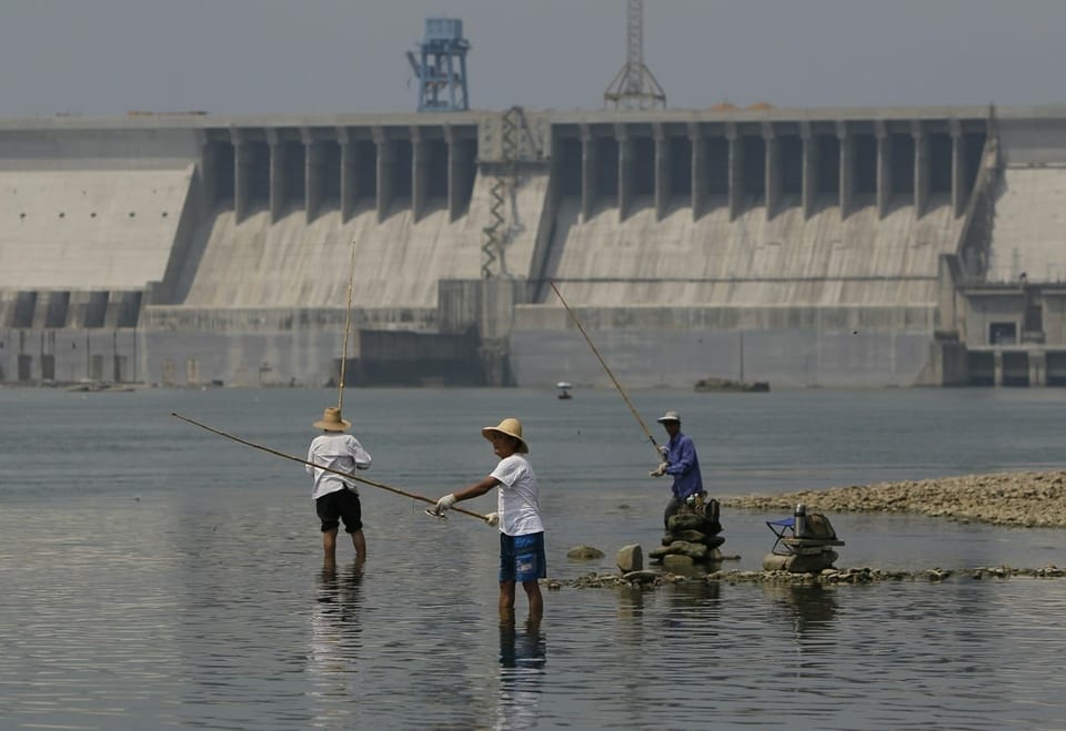 Drei Fischer fischen mit ihren Bambusruten vor dem grossen Staudamm.