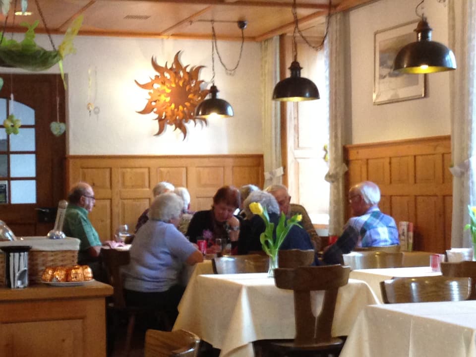 Zu sehen ist eine Gruppe Senioren. Sie sitzen in einer traditionell eingerichteten Beiz an einem Tisch.