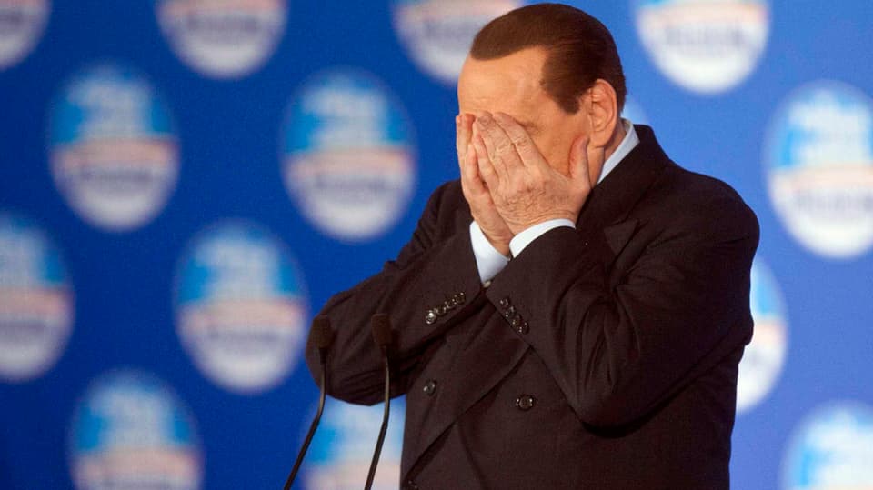 Berlusconi hält sich mit den Händen die Augen zu.