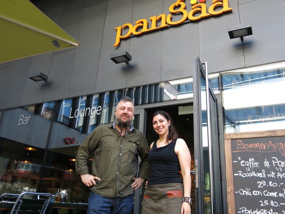 Ein Mann und eine Frau stehen vor ihrem Restaurant.