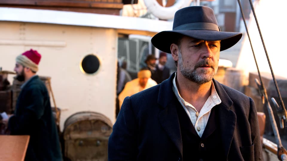Russel Crowe steht auf einem Schiff, das halbe Gesicht ist von der Sonne beschienen.