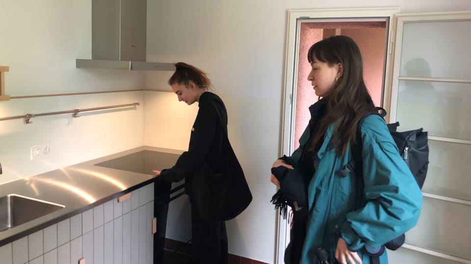 Zwei junge Frauen besichtigen eine frisch renovierte Küche in einer sanierten Mietwohnung. 