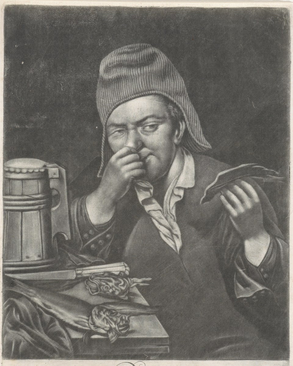 Mann sitzt an Tisch, hält mit einer Hand einen stinkenden Gegenstand, mit der anderen hält er sich die Nase zu. 