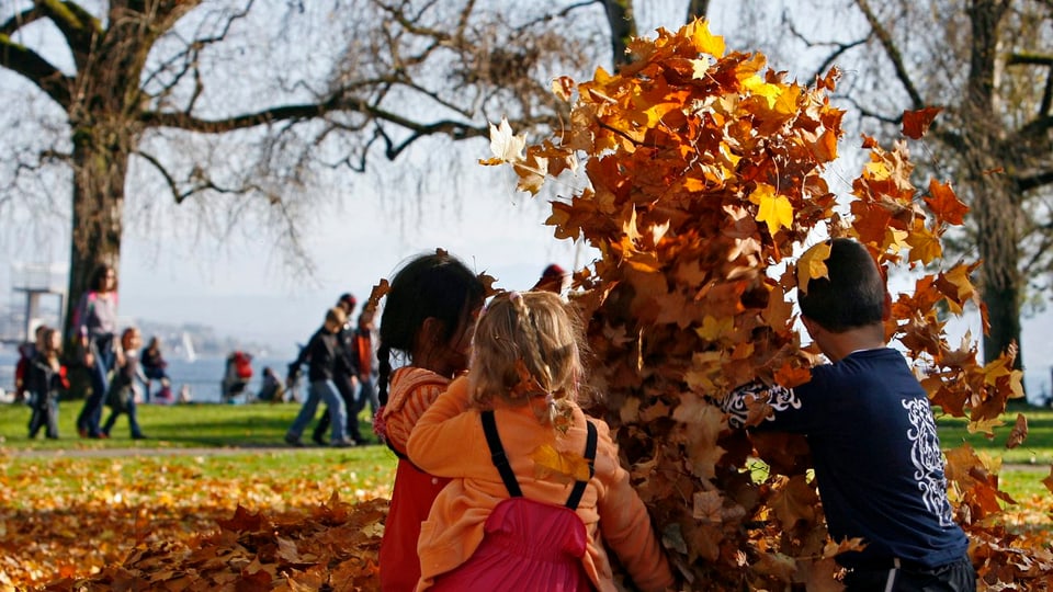 Kinder beim Spielen im Herbstlaub