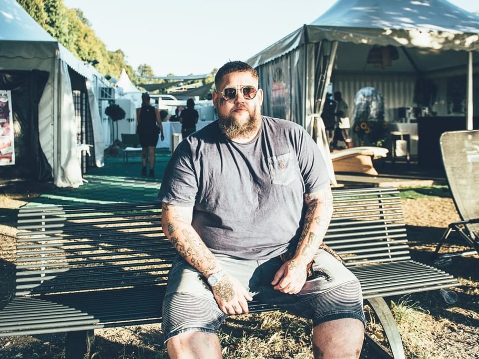 Rag’n’Bone Man sitzt auf einer Bank