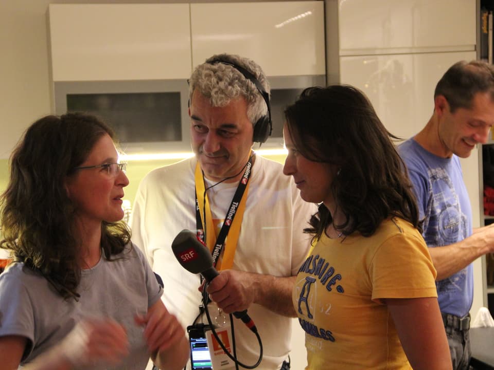 Reporter hält Mikrofon zwischen Katia Ambrosini und einen Gast.