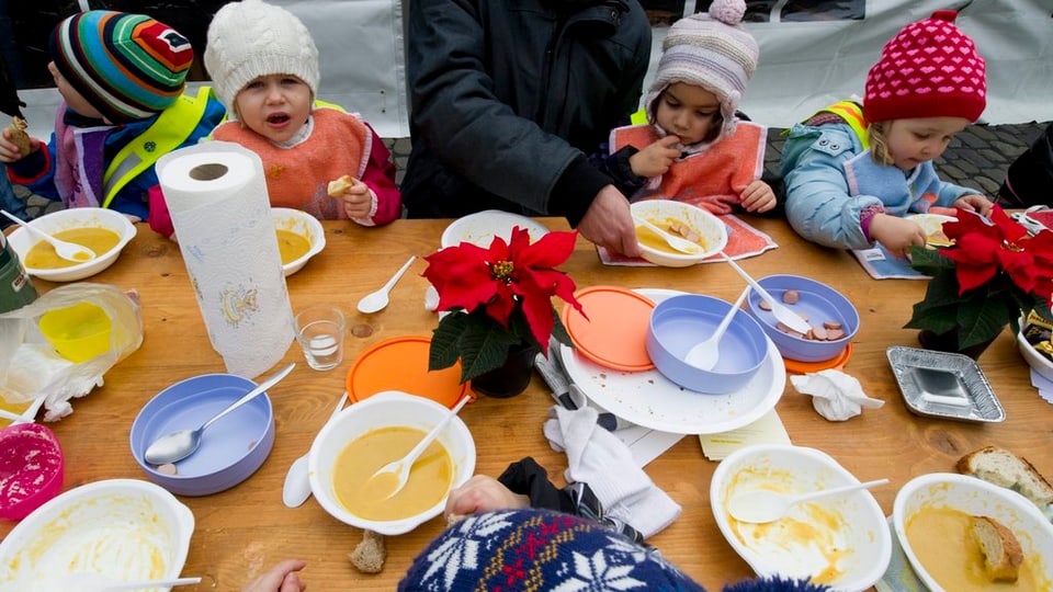 Kinder mit Kappe essen Suppe