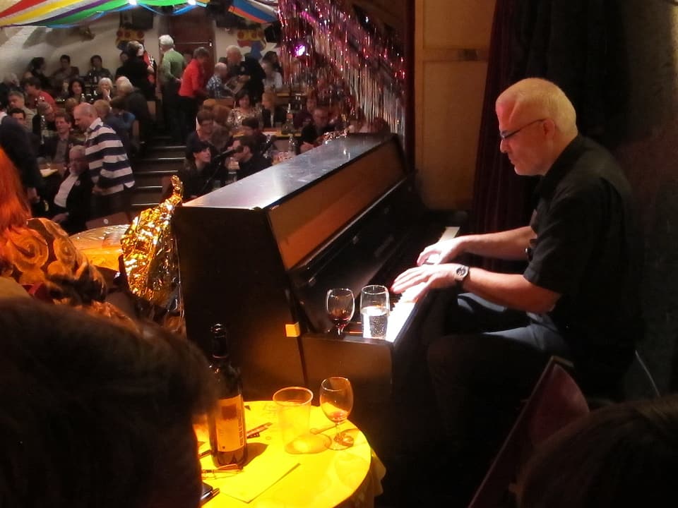 Mann am Klavier, im Hintergrund Publikum