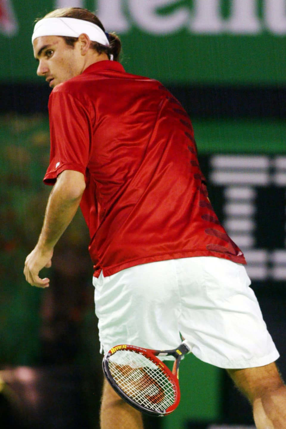 Federer schlägt einen Ball mit dem Rücken zum Netz zwischen seinen Beinen hindurch.