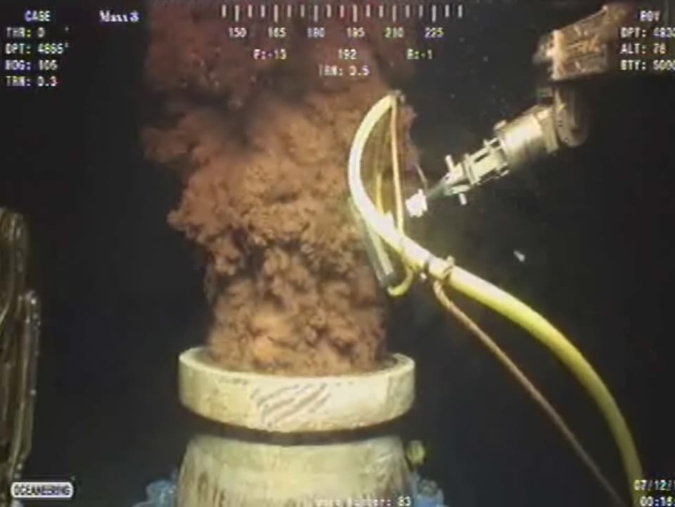 Öl sprudelt aus einem Rohr unter Wasser.