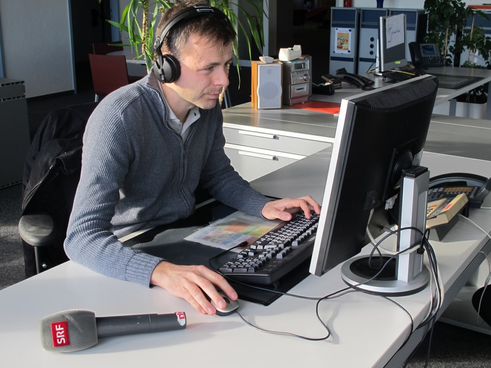 Redaktor Mario Gutknecht sitzt mit einem Kopfhörer am Computer-Arbeitsplatz