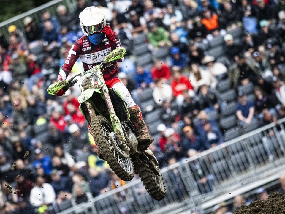 Motocross rider in the air in front of the crowd.