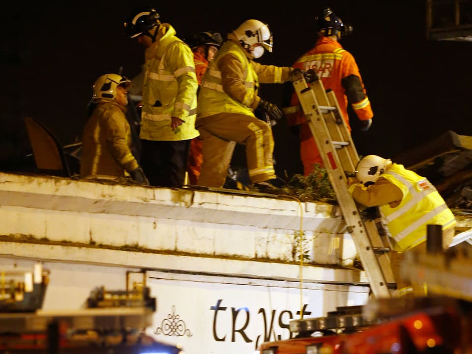 Einsatzkräfte der Feuerwehr mit einer Leiter auf dem Dach des betroffenen Pubs.