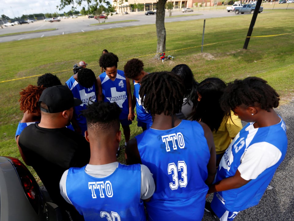 Eine Gruppe afroamerikanischer Teenager im Kreis stehend und betend.