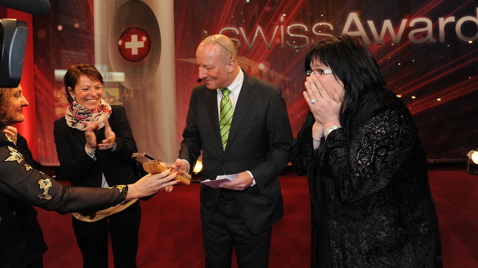 Übergabe des Pokals zur Weitergabe an Karin Boss-Röthlisberger Heidi Ungerer von Radio SRF 1 übergibt den Pokal «Helden des Alltags» zur Weitergabe an Roger de Weck.
