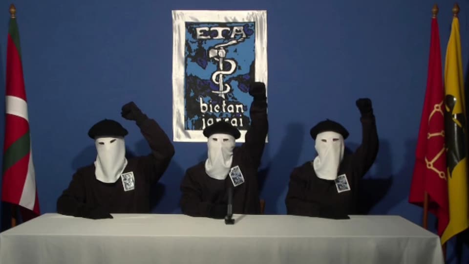 Drei ETA-Mitglieder mit weissen Masken strecken die Fäuste in die Luft.