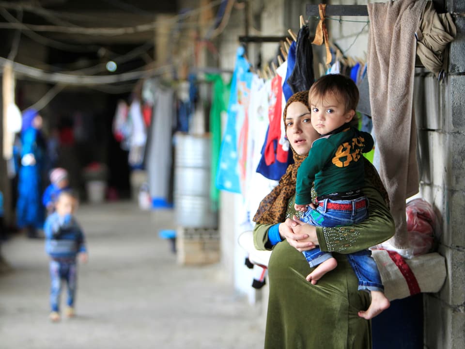 Eine schwangere Syrerin mit einem Kind auf dem Arm.