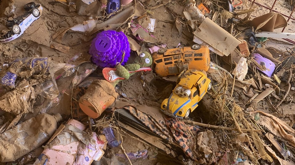 Verstreutes Spielzeug liegt vor einem beschädigten Haus in Darna.