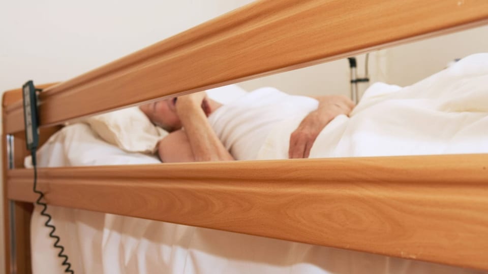 Am Bett eines Patienten in einem Pflegeheim sind Bettgitter angebracht um ihn am aussteigen oder rausfallen zu hindern