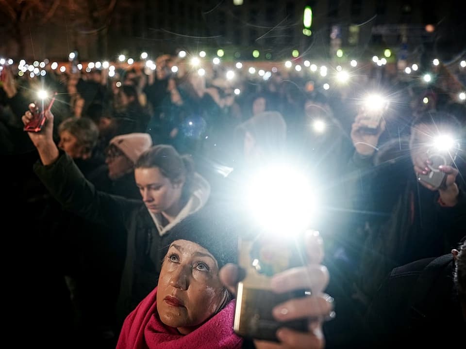 Demonstranten halten nach dem Tod von Alexej Nawalny ihre Smartphonelampen vor der russischen Botschaft in die Höhe.