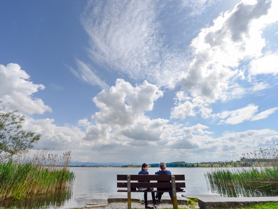 Ein älteres Paar sitzt vor einem See. (keystone)