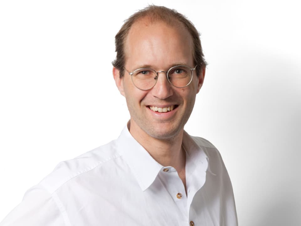 Porträt von Andreas Kronenberg in weissem Hemd und mit Brille.