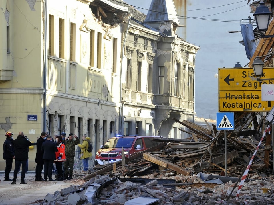 Schuttmassen auf einer Strasse, Helfer, auf einem Strassenschild ist die Richtung nach Zagreb angegeben.