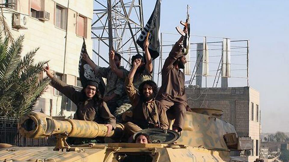 Kämpfer der Terrorgruppe Islamischer Staat (IS) lachen auf einem Panzer.