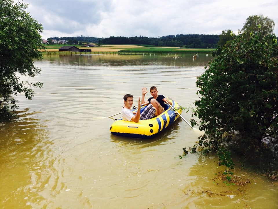 überflutetes Feld, zwei Jugendliche in einem Gummiboot