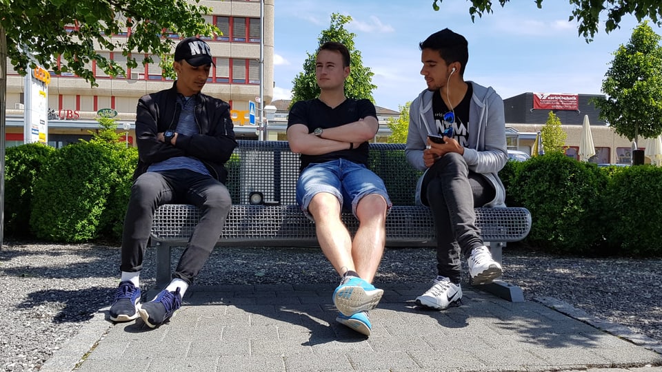 drei Männer sitzen auf einer Bank