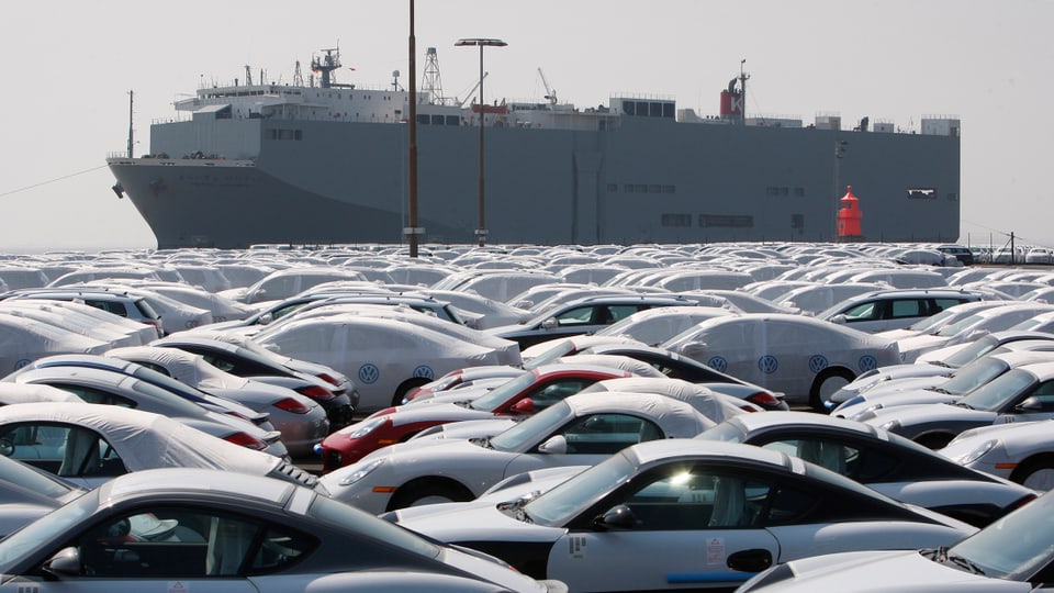 Neue Autos der Marke Volkswagen vor einem Transportschiff.