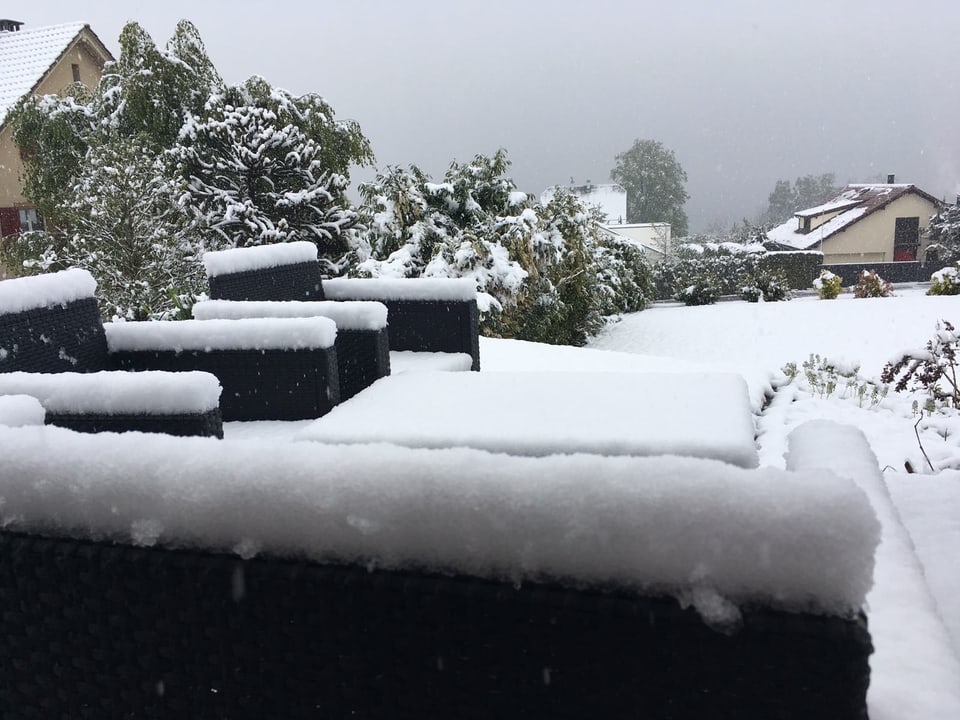 Schnee auf Gartenmöbel und im Garten.