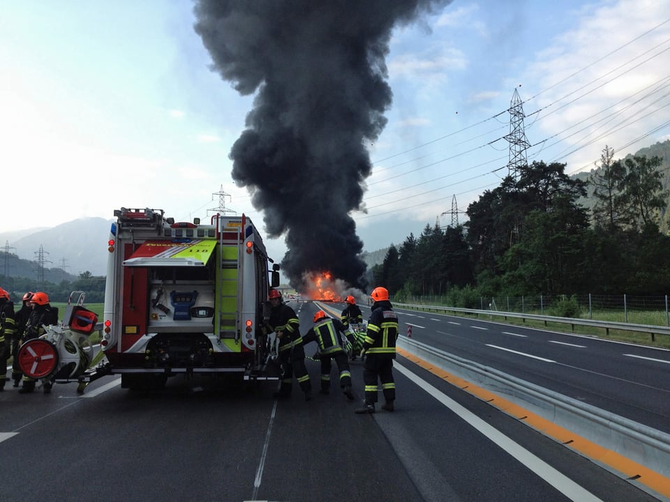 Fahrzeug der Feuerwehr. Im Hintergrund sieht man die hohe schwarze Rauchwolke.