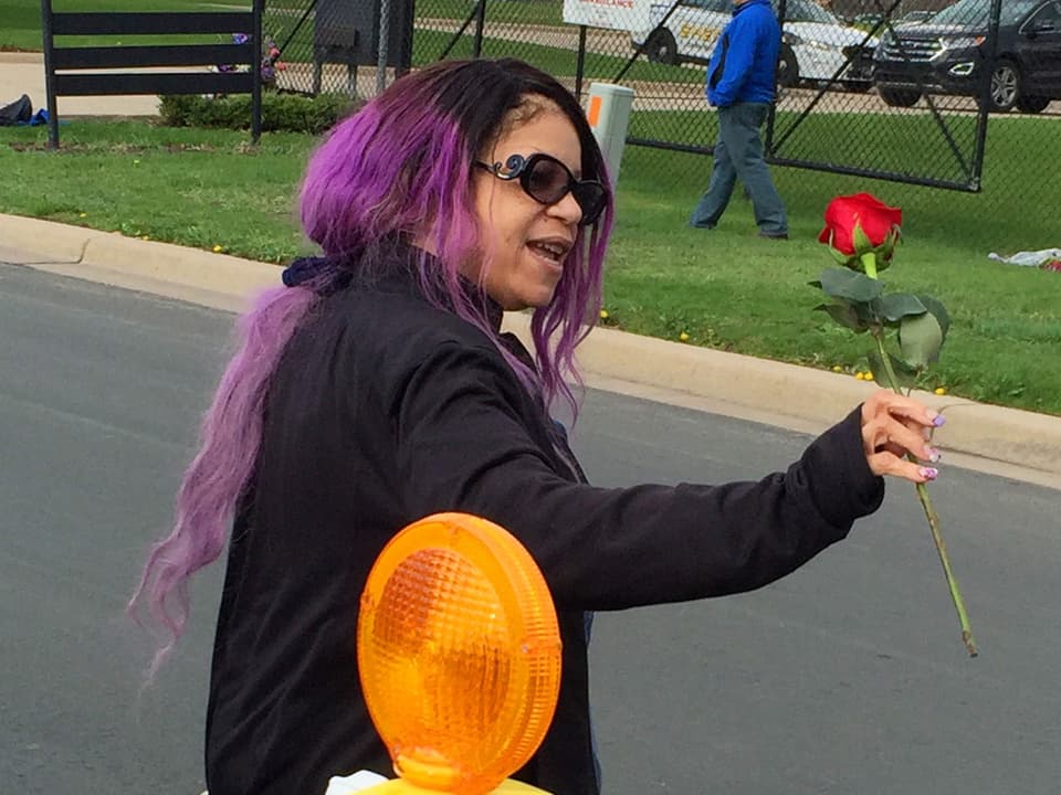 Frau mit violetten Haaren und einer Rose in der Hand